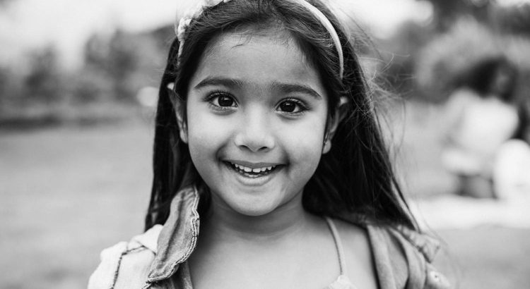 Smiling Indian schoolgirl holding a notebook outdoors in Ajman